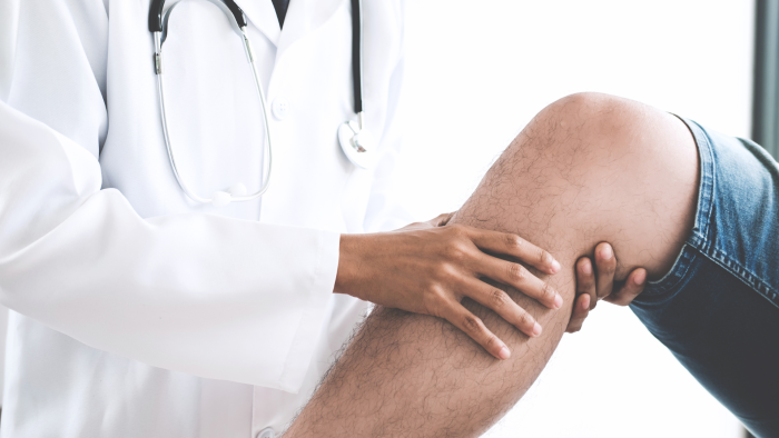 Doctor inspecting the knee joint of a patient.