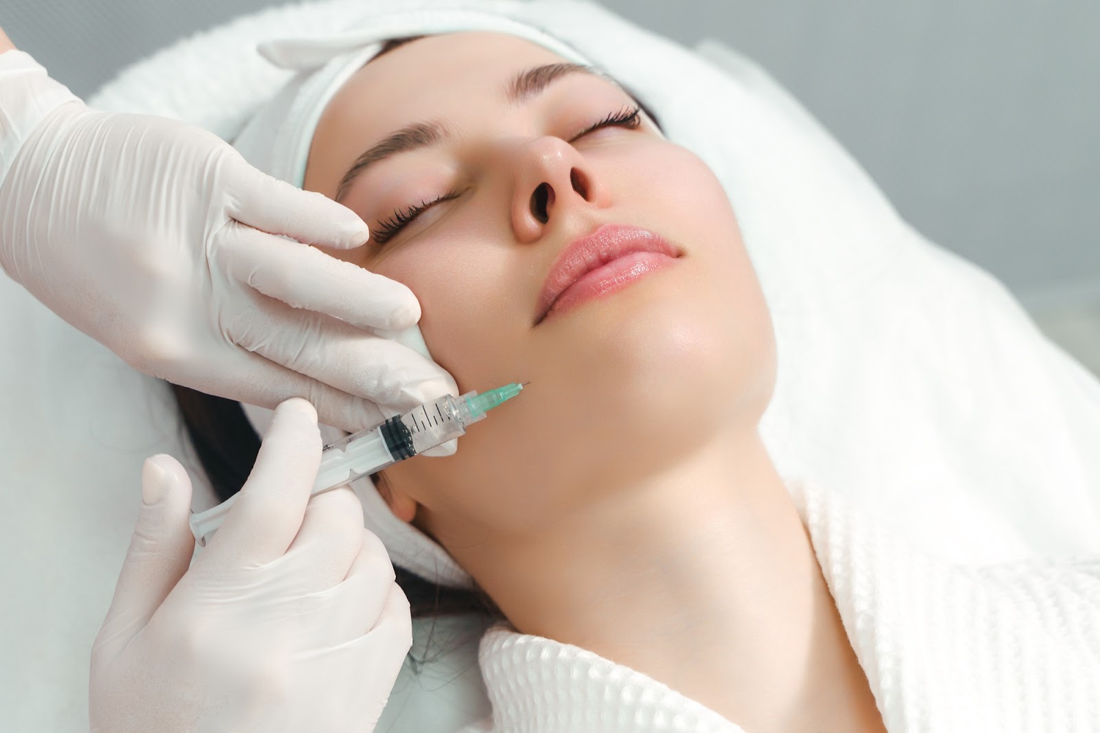 Female patient receiving Restylane injection in a beauty clinic to achieve facial rejuvenation.