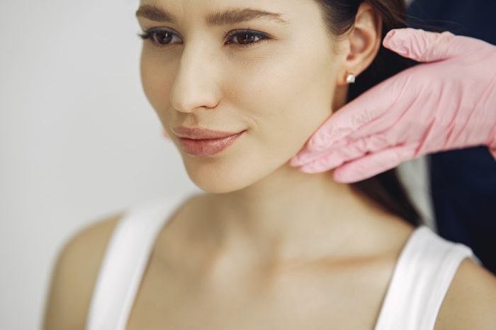 An aesthetic specialist inspecting a woman's facial structure to determine where to inject Restylane.