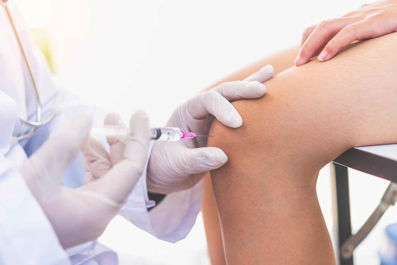 hand with gloves injecting the knee
