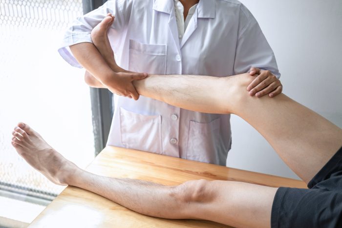 Doctor or Physiotherapist working examining treating injured leg