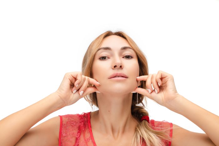 Nice caucasian woman shows exercises for firmness of the face, picture isolated on white background
