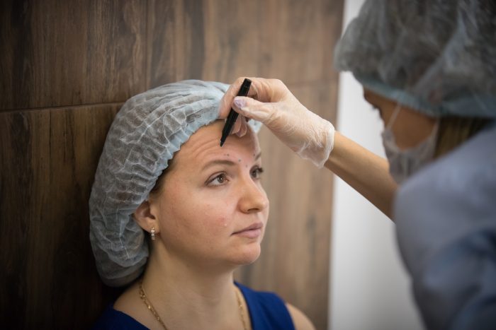 Woman in a cosmetology clinic. Specialist scatching on client face