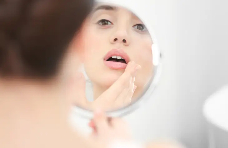 Woman looking at lips in mirror