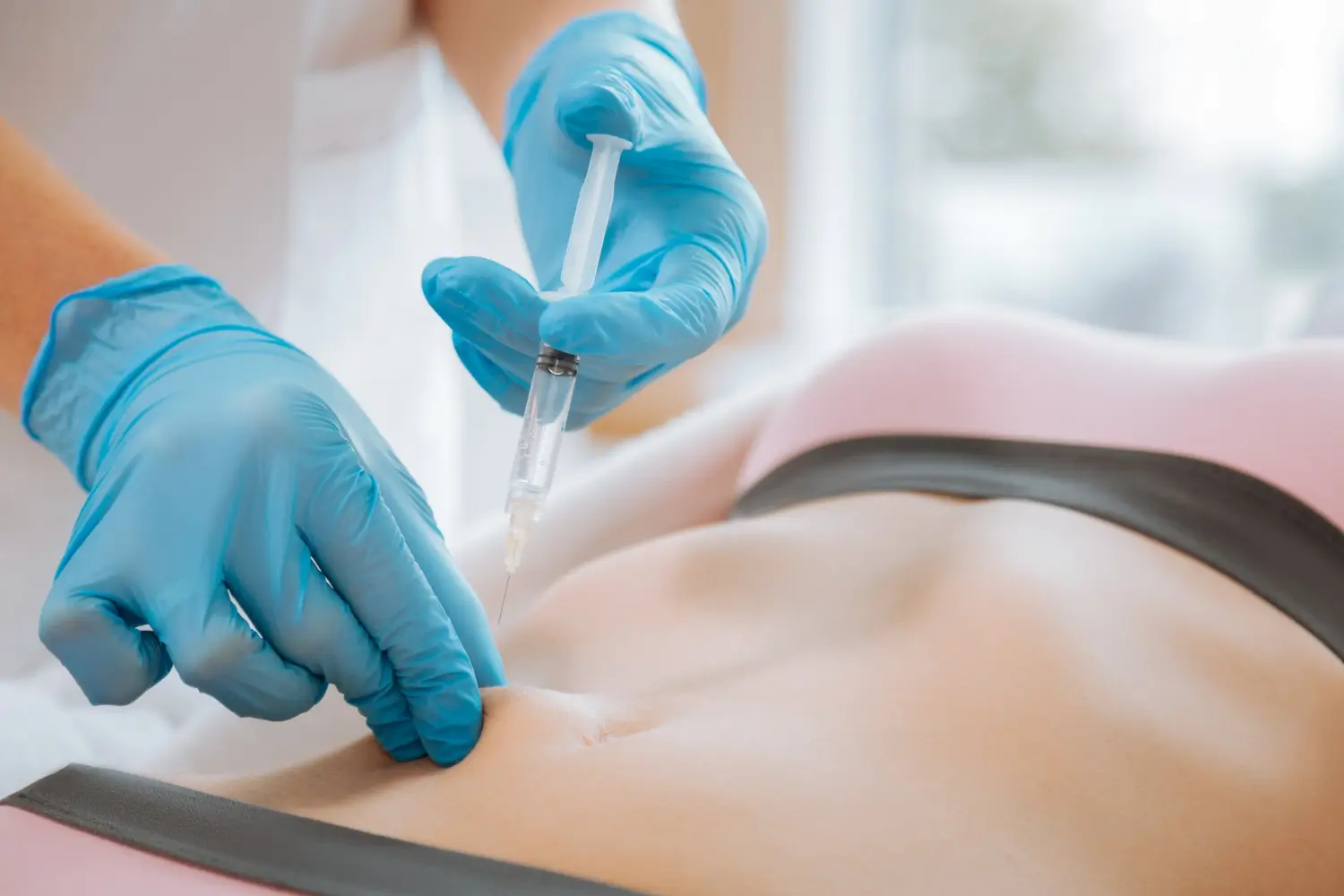 Doctor carefully injects the treatment for fat reduction on the patient's abdomen.