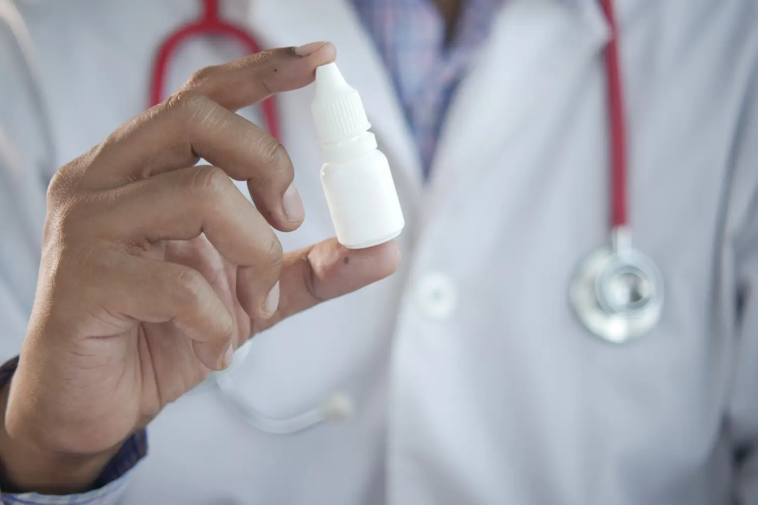 Doctor presents the bottle of eye drop solution before using it.