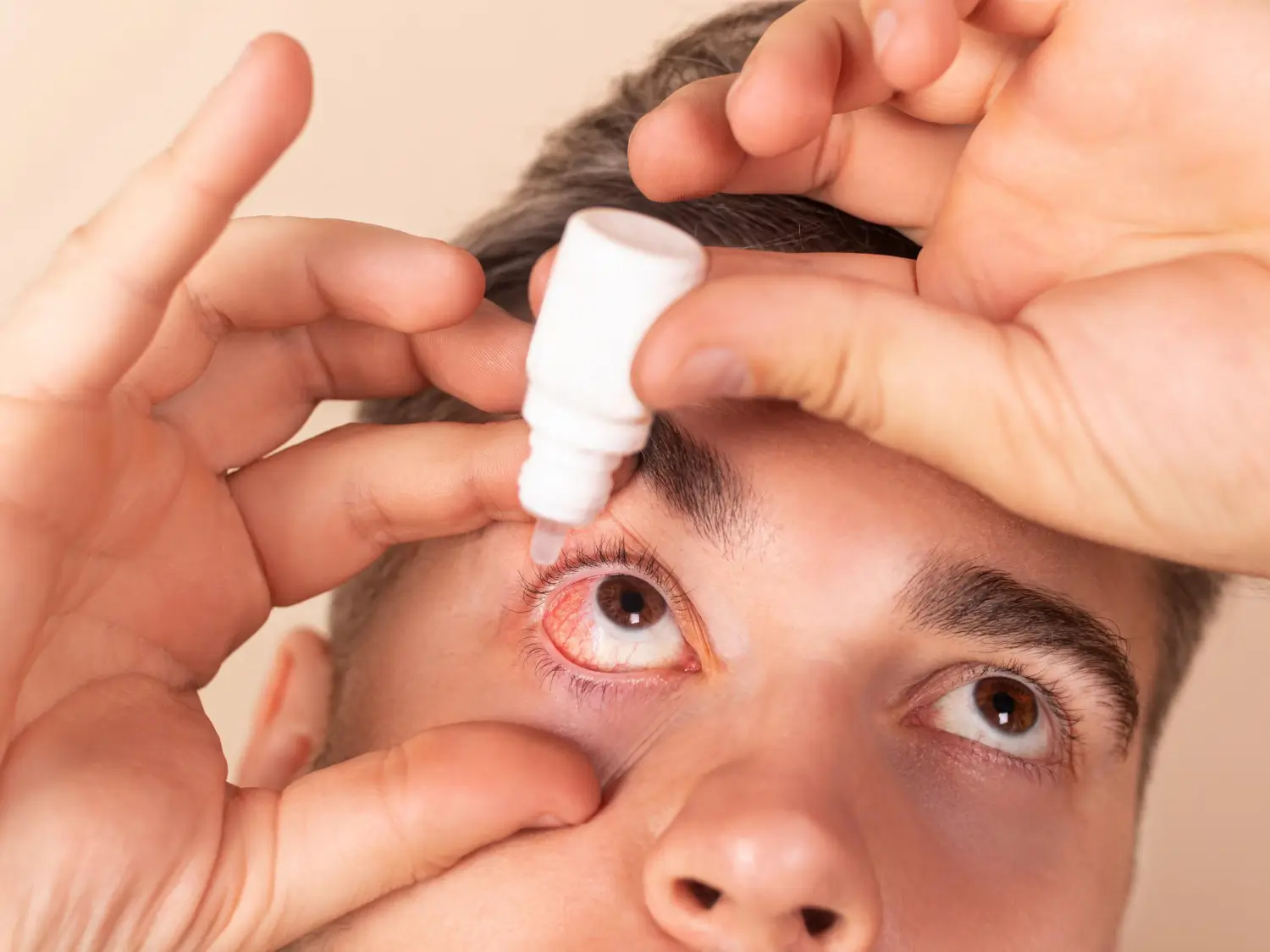 putting the eyecare solution on his eyes